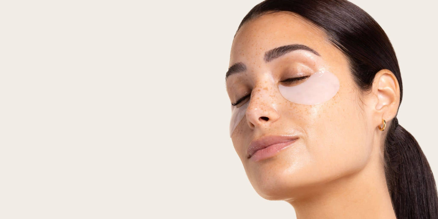 woman wearing skin remedy under eye patches light cream background