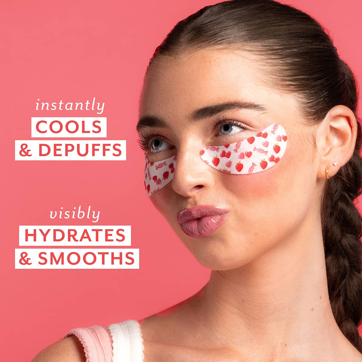 Woman wearing red heart eye patches with text on a pink background text 'instantly cools and depuffs and visibilty hydrates and smooths'.