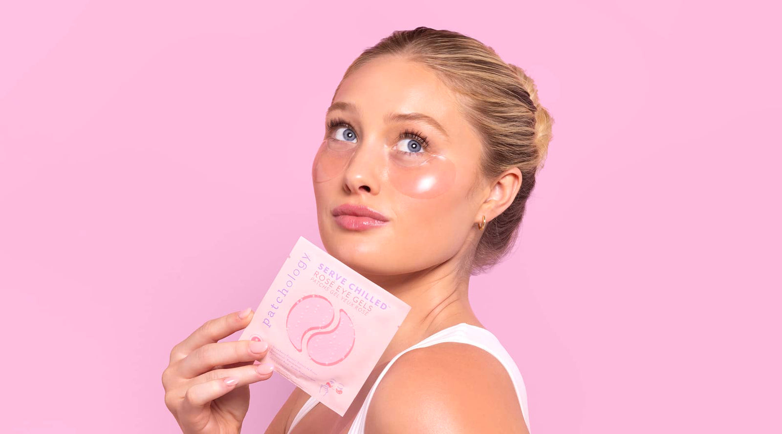woman on a bright pink background wearing serve chilled rose eye patches