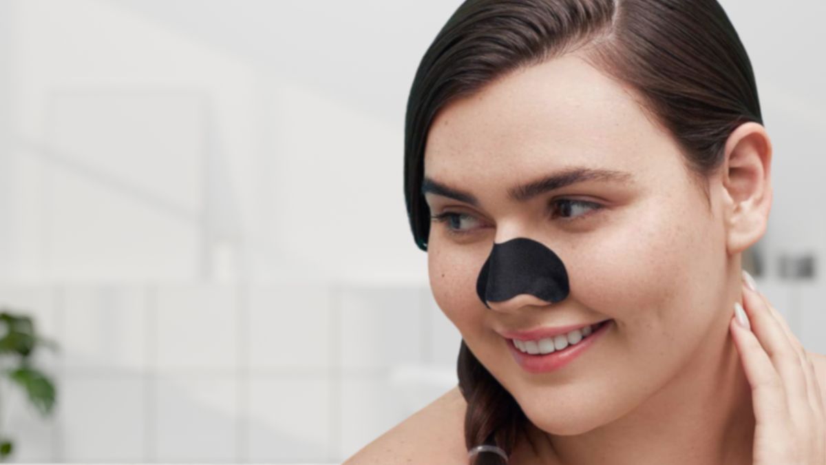 Woman wearing black nose pore strip on nose for deep cleansing skincare treatment
