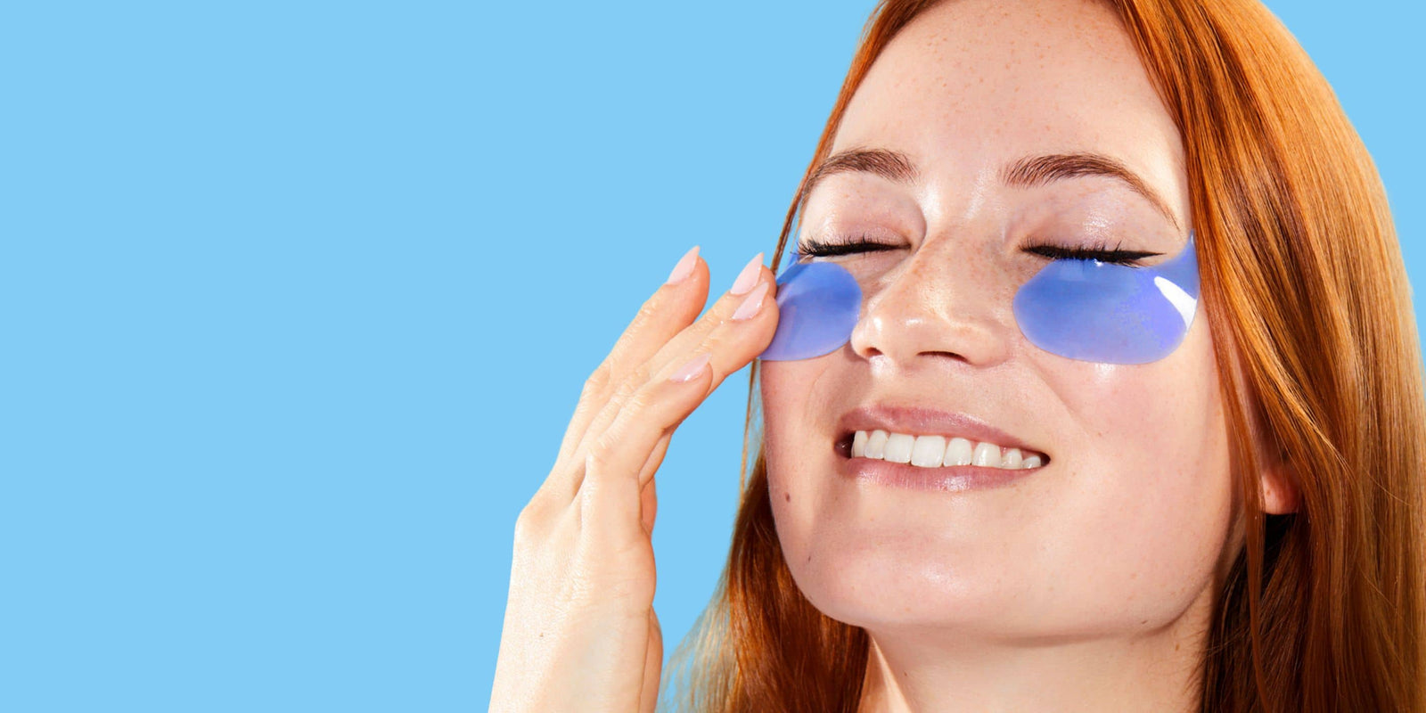 Woman with blue hydrogel under-eye patches gently pressing skin, showing soothing and hydrating skincare treatment