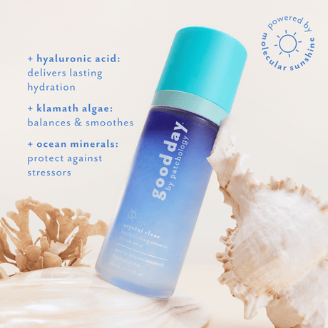A bottle of Good Day Crystal Clear moisturizing mineral sunscreen shown on a light cream background with decorative seashells and blue text describing benefits.