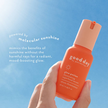 A hand holds a bottle of Good Day Glow Potion serum illuminator against a bright blue sky with sun rays. White text on the left reads 'powered by molecular sunshine' and 'mimics the benefits of sunshine without the harmful rays for a radiant, mood-boosting glow.