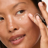 Woman gently applying Eye Pillow 360° Brightening Eye Cream beneath her eye.