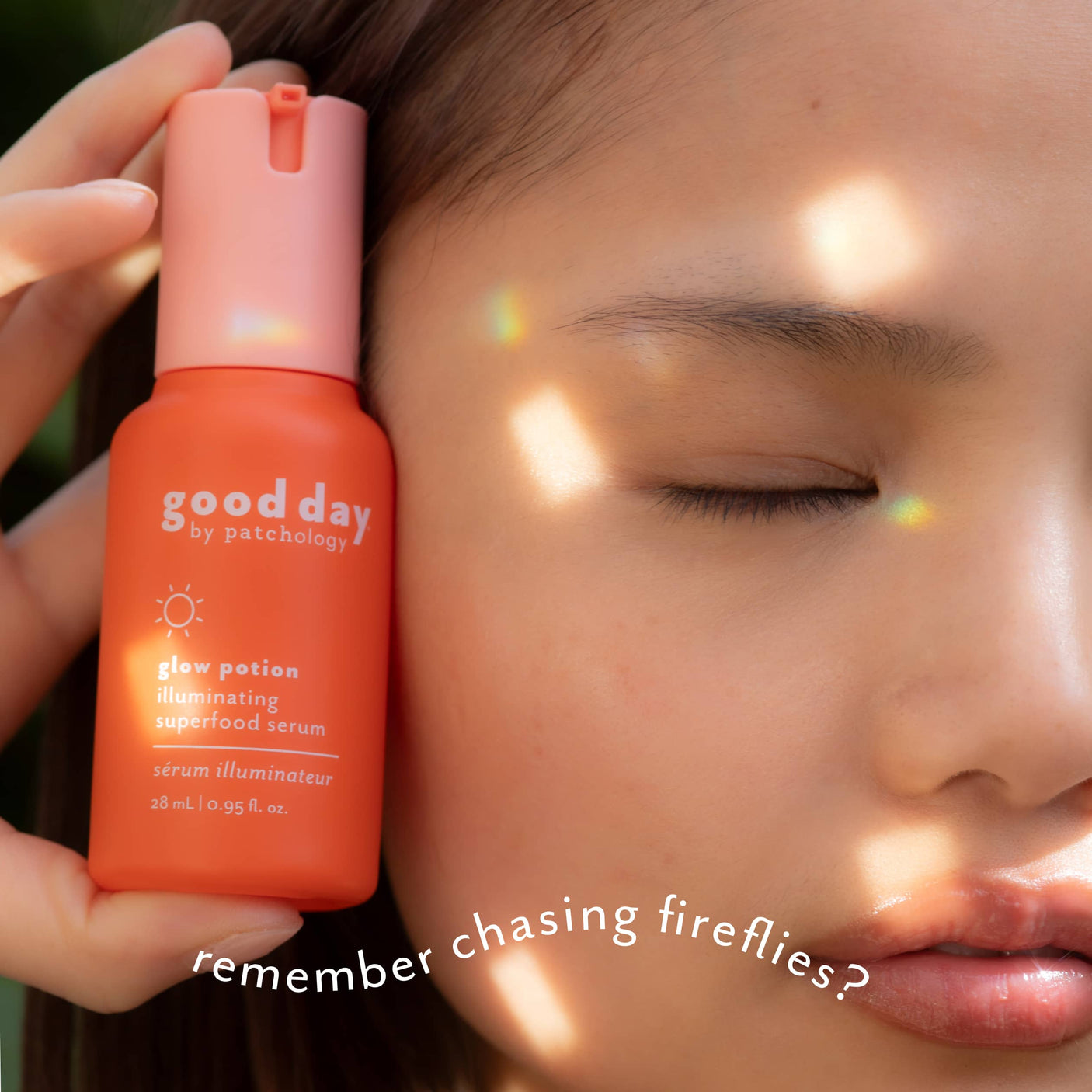A close-up lifestyle shot of a woman with her eyes closed, holding a bottle of 'good day glow potion' against her cheek. The bottle is a vibrant orange with a pink cap.