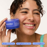 Smiling woman holding Five-to-Nine Dreamy Overnight Recovery Balm, highlighting deep moisture, stronger-looking skin, and visible brightening.