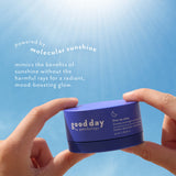 Hands holding Five-to-Nine Dreamy Overnight Recovery Balm under bright sunlight against a blue sky.