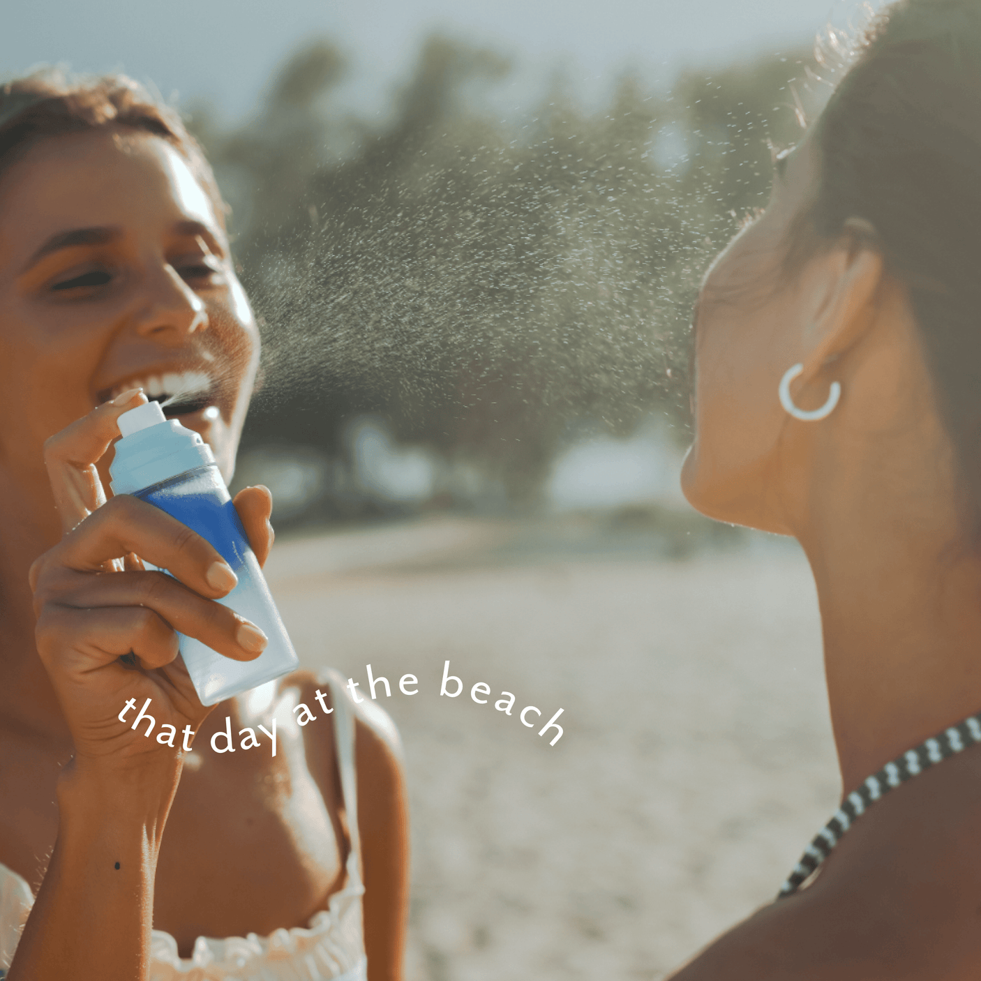 Two women on a beach spraying each other with a blue and white sunscreen bottle, with the text 'that day at the beach' overlaid on the image.